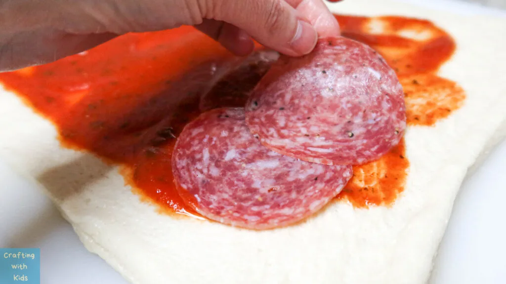 adding salami to the pizza calzone