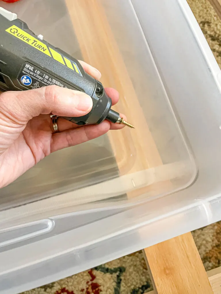 drilling screws in plastic bin into trundle