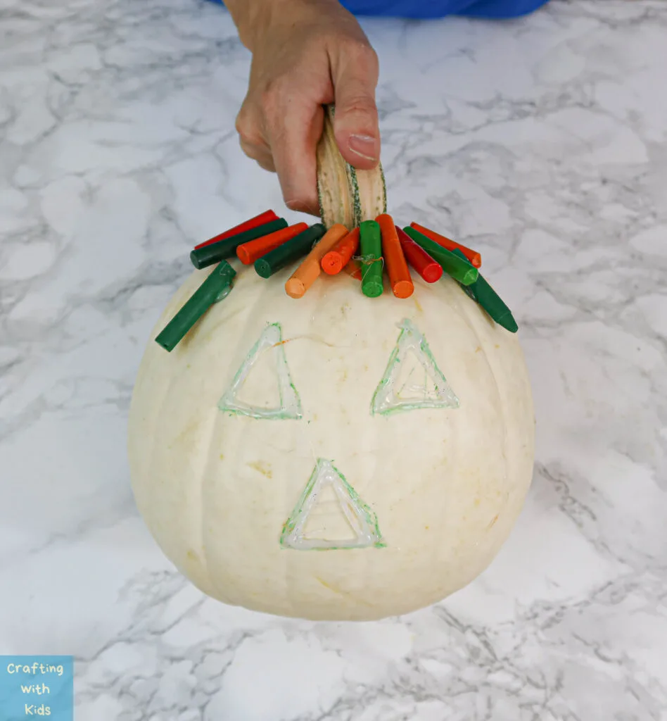 gluing crayons to pumpkin for no carve pumpkin art