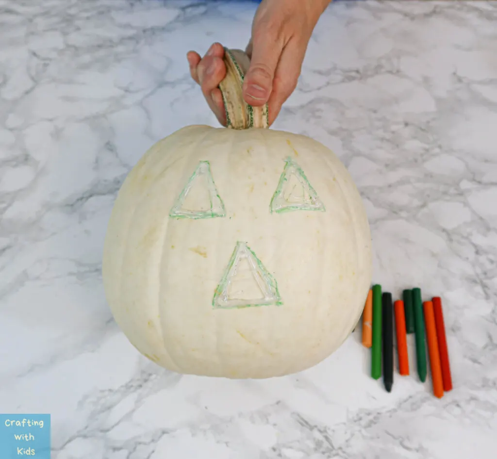 applying hot glue to make eyes and nose on pumpkin