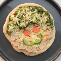 pizza with veggies and smiley face