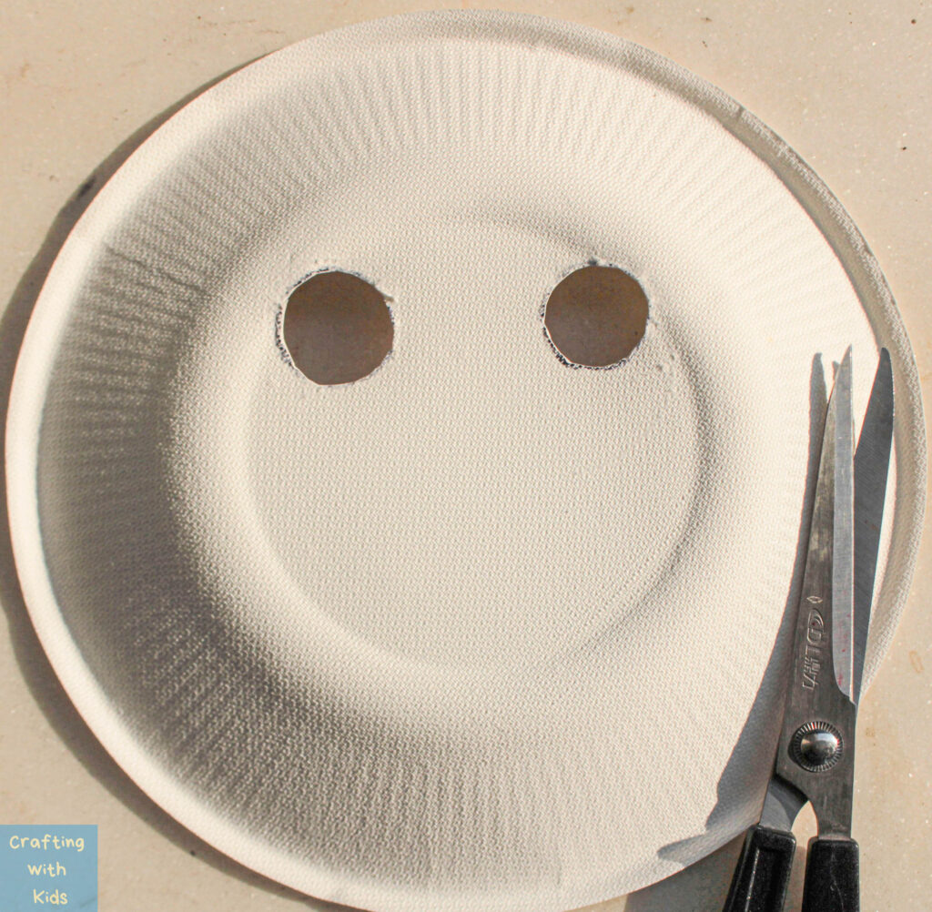 cutting eyes out of paper plate for pumpkin